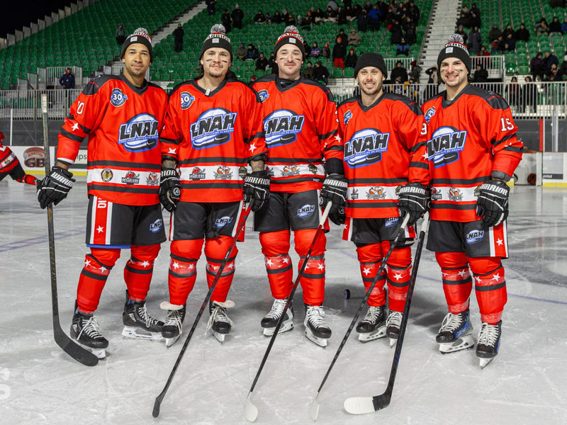Five hockey players in red uniforms with visible logos on an ice rink.